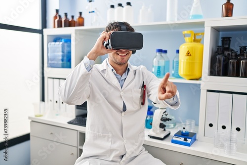 Young hispanic man scientist using virtual reality glasses at laboratory