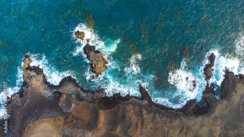 zenithal aerial drone view of waves crashing against cliffs