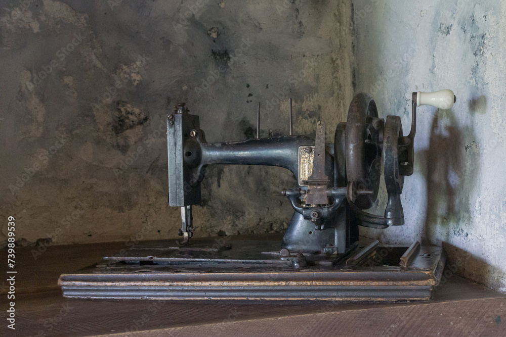 Old manual sewing machine on the background of a cement wall Old manual sewing machine on the background of a cement wall