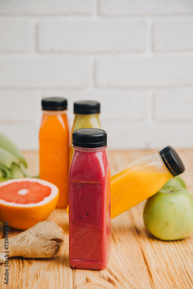 Fruit and vegetable smoothies in transparent plastic bottles. Red, green, orange smoothies on a wooden table with women's hand. The concept of healthy eating. Front view Fruit and vegetable smoothies in transparent plastic bottles. Red, green, orange smoothies on a wooden table with women's hand. The concept of healthy eating. Front view
