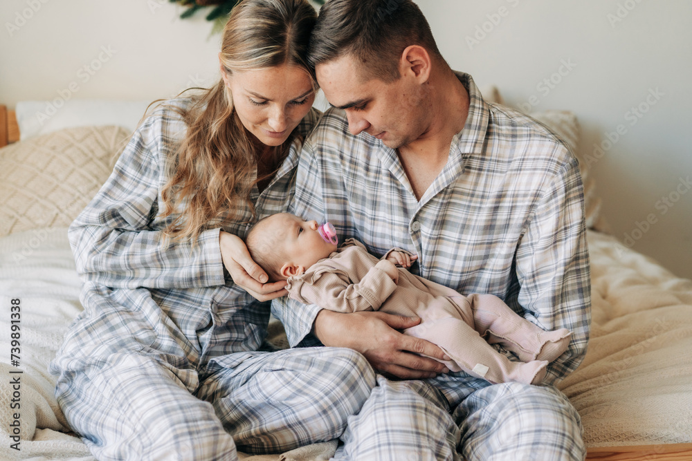Mother and father are holding an adorable newborn baby sucking a pacifier. Family relationships. Mother and father are holding an adorable newborn baby sucking a pacifier. Family relationships.