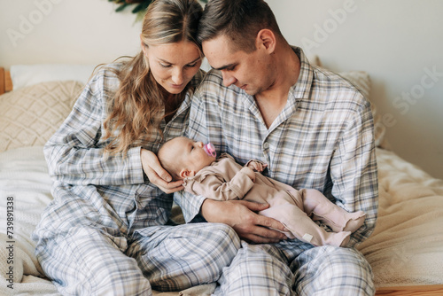 Mother and father are holding an adorable newborn baby sucking a pacifier. Family relationships.