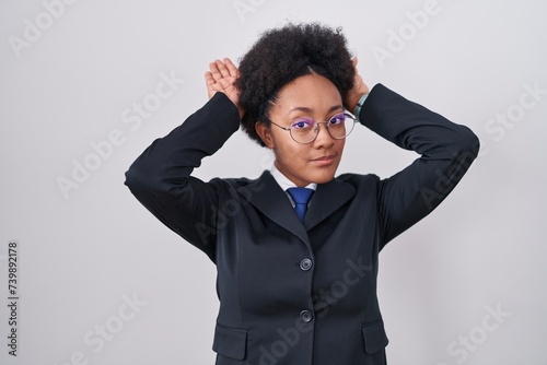 Beautiful african woman with curly hair wearing business jacket and glasses doing bunny ears gesture with hands palms looking cynical and skeptical. easter rabbit concept. photo