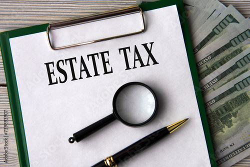 ESTATE TAX - words on a white sheet on the background of banknotes, magnifying glass and pen