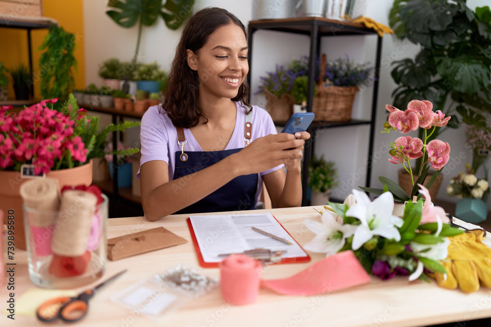 Young african american woman florist smiling confident using smartphone at flower shop