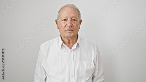 Senior man standing with serious face over isolated white background