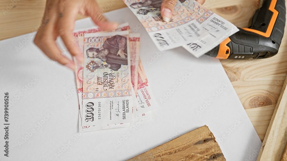 Obraz premium A person handles icelandic krona on a workbench, hinting at a transaction or financial topic in a work setting.