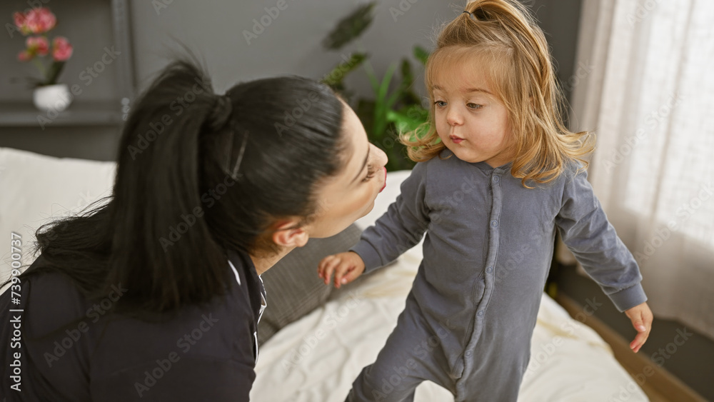 A mother and her young daughter enjoy a tender moment together in a cozy bedroom setting A mother and her young daughter enjoy a tender moment together in a cozy bedroom setting