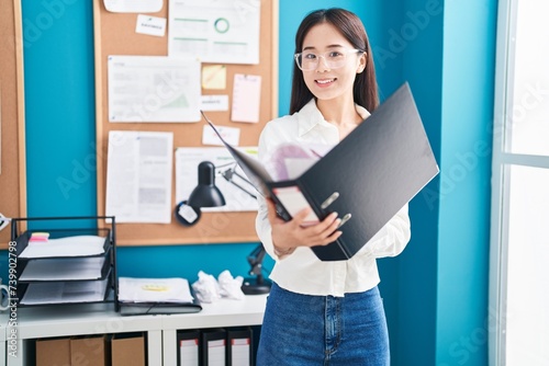 Young chinese woman business worker reading document at office