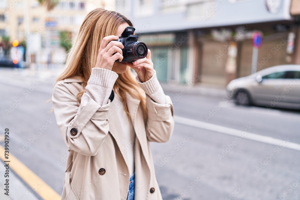 Young blonde woman susing professional camera at street