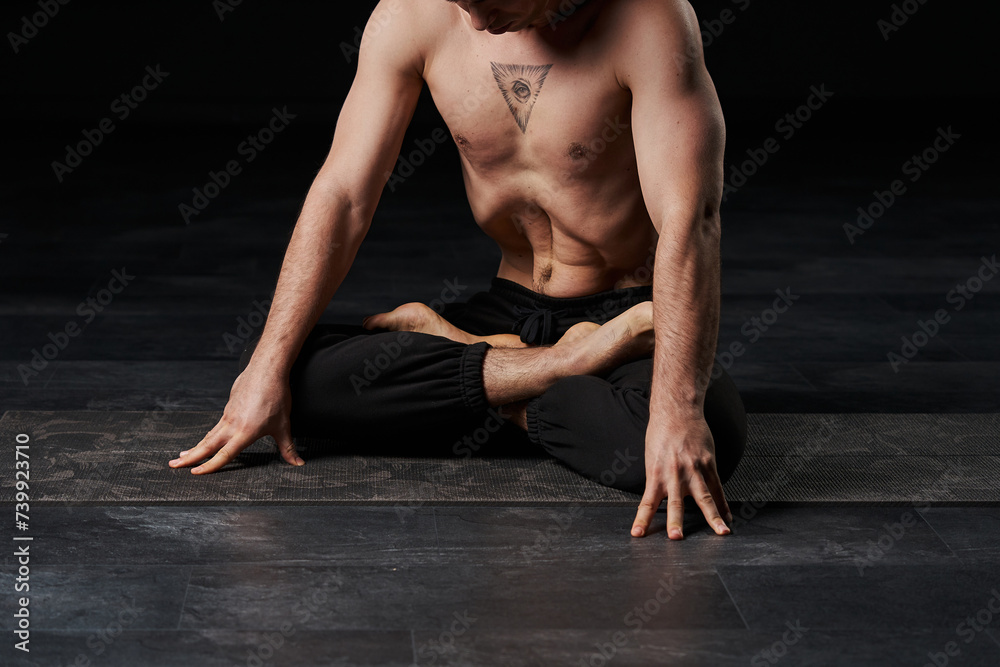 Lotus-posed man performs stomach vacuum, showcasing an all-seeing eye tattoo on his chest, radiating spiritual wisdom.