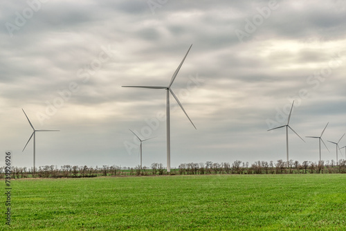 Wind turbines generating electricity in a green field. Green power generation concept.