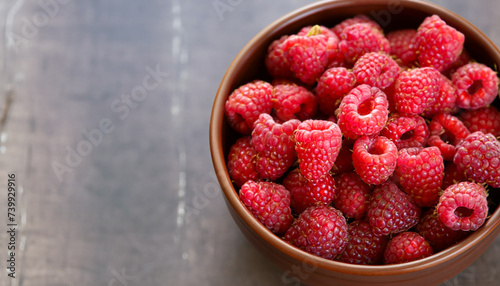Fresh raspberries in brown bowl, shallow focus with copy space; overhead shot