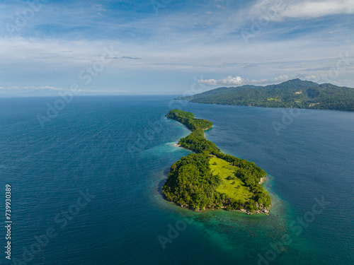 Small island with rocky shoreline surrounded by blue ocean. Samal Island. Davao, Philippines.