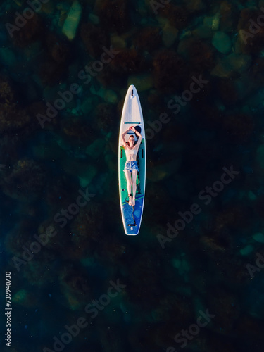 Woman relax on stand up paddle board at sea. Enjoying on sup board. Aerial view © artifirsov