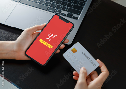 Hands are holding a credit card while using a smartphone application for online shopping.