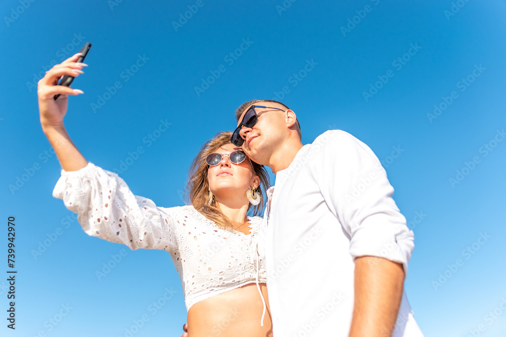 Young happy couple taking selfie on the beach. Summer vacations concept. Young happy couple taking selfie on the beach. Summer vacations concept.