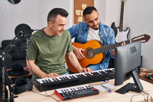 Two men musicians playing piano and classical guitar at music studio photo