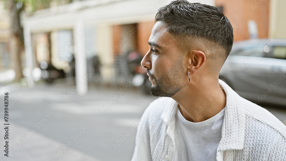 Handsome young adult man with a beard poses on a city street, exuding confidence and style in an urban setting. Handsome young adult man with a beard poses on a city street, exuding confidence and style in an urban setting.