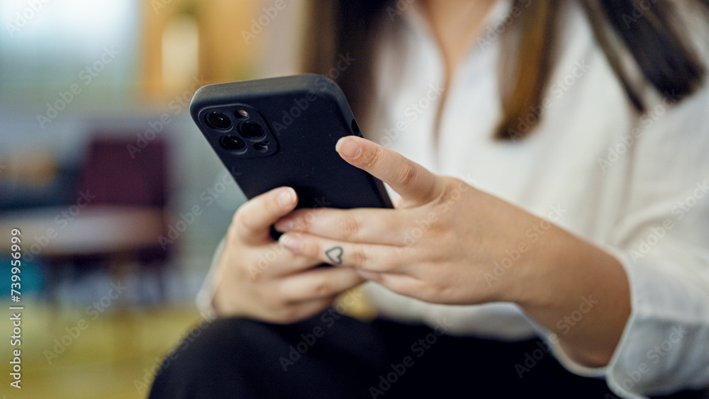 Fototapeta premium Young beautiful hispanic woman using smartphone at the office