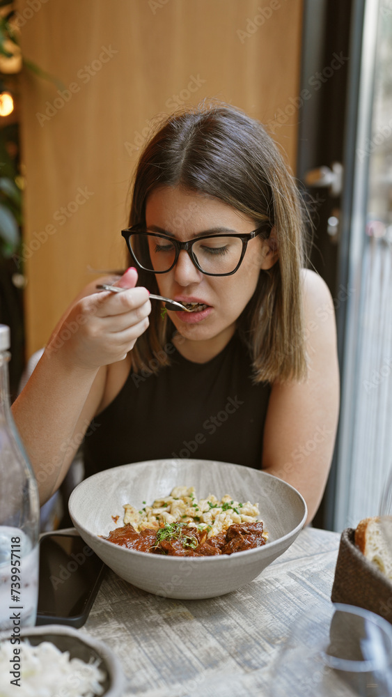 A young woman enjoys a gourmet meal at a modern restaurant, depicting dining, lifestyle, and food themes.