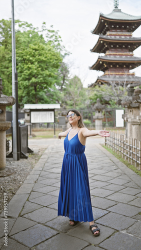 Beautiful young hispanic woman wearing glasses with open arms smiling looking around at ueno park temple