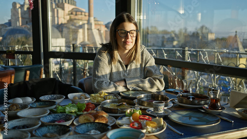 A young woman enjoys breakfast in a restaurant with a view of the hagia sophia in istanbul, turkey photo