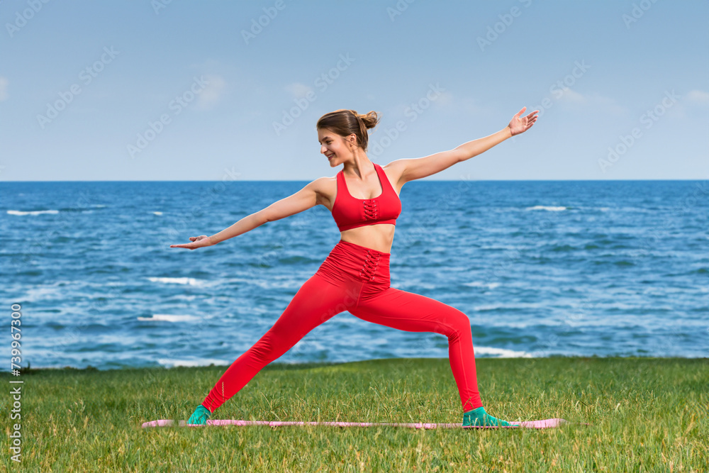 Portrait of happy athletic woman doing yoga warrior pose on the sea shore, Seaside mindfulness: Alone, a young woman stretches in yoga, captivated by the ocean's calm Portrait of happy athletic woman doing yoga warrior pose on the sea shore, Seaside mindfulness: Alone, a young woman stretches in yoga, captivated by the ocean's calm