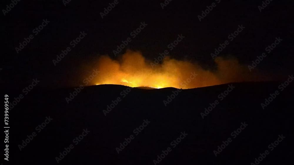 A large forest fire in the mountains flares up and intensifies. At night you can see the fire burning A large forest fire in the mountains flares up and intensifies. At night you can see the fire burning