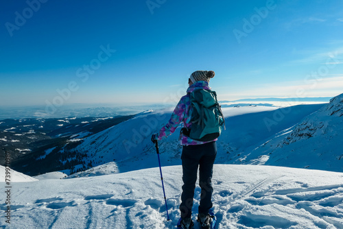 Woman in snowshoes on snow covered mountains of Kor Alps, Lavanttal Alps, Carinthia Styria, Austria. Winter wonderland in Austrian Alps. Ski touring and snow shoe tourism. Tranquil serene atmosphere