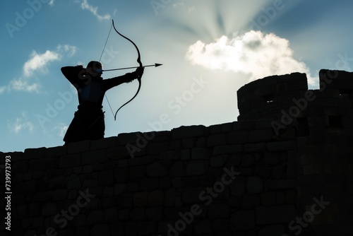 archer silhouetted against sky on fortress wall photo