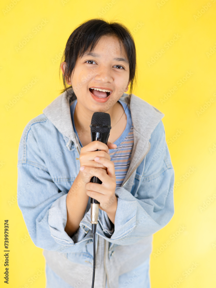 Young girl sing song and dance happily on yellow background. Stock