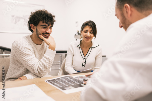 Smiling doctor discusses X-rays with patients at clinic photo