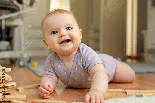 Adorable baby girl, six months old, lying, floor, playing, wooden, ecological, construction blocks, early development concept. High quality photo