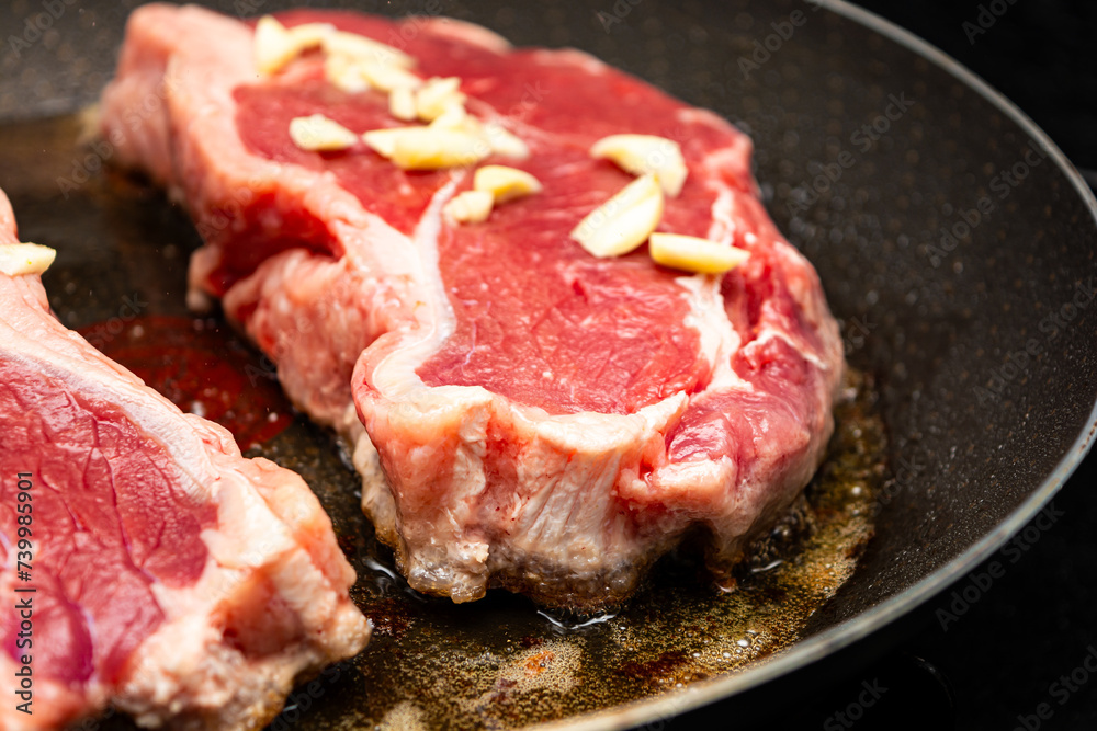 frying two sirloin steaks with garlic for dinner