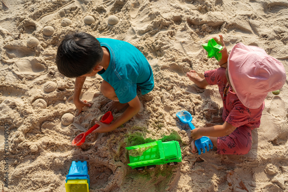 Adorable little boy and girl enjoying play toy on sea sand beach Adorable little boy and girl enjoying play toy on sea sand beach