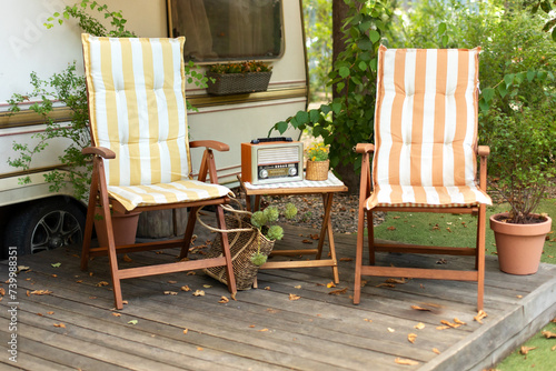 Wooden deckchair and Brown vintage radio near campsite on caravan or camper van. Lounge sunbed in garden. The FM channel is playing music, a stylish retro radio player stands on a wooden table. 