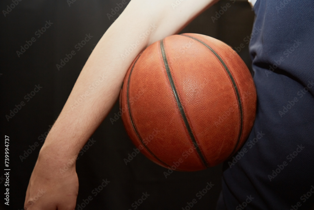hand holds a lit basketball near the hip on a black background, close-up, the start of the game hand holds a lit basketball near the hip on a black background, close-up, the start of the game