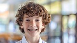 Closeup portrait of smiling smart curly haired school boy wearing braces on teeth looking at camera. Education concept