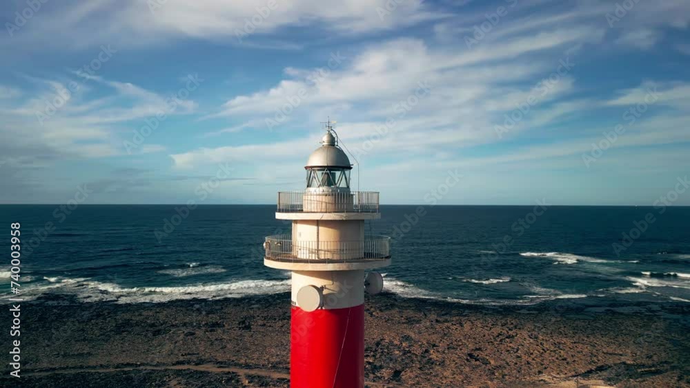 The 19th century red and white bands Faro del Tostón lighthouse located on the northwest coast of Fuerteventura in the Canary Islands. A lighthouse against the background of the blue sky and the ocean The 19th century red and white bands Faro del Tostón lighthouse located on the northwest coast of Fuerteventura in the Canary Islands. A lighthouse against the background of the blue sky and the ocean