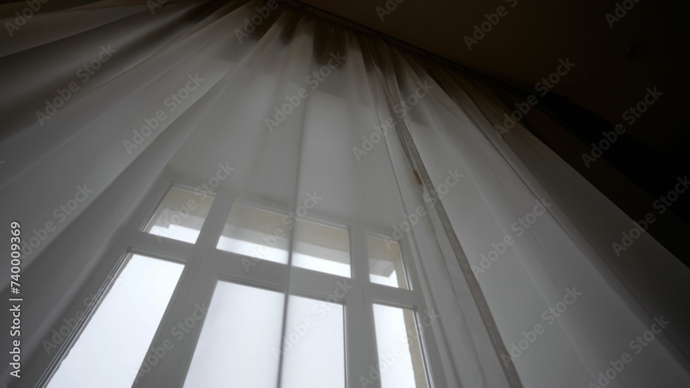 Naklejka premium Delicate translucent curtains on a large window in a hotel. Large window with transparent tulle. Large bright window with white curtains.