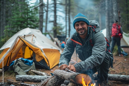A rugged man in outdoor clothing tends to the crackling campfire, surrounded by the serenity of nature, as he prepares for a cozy night under the stars with his trusty tent and hiking equipment nearb photo