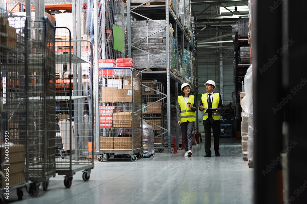 focused supervisor in safety vest and hard hat inspecting warehouse with clipboard, professional focused supervisor in safety vest and hard hat inspecting warehouse with clipboard, professional