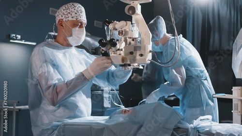 A surgeon looks through a microscope at a patient's eyes in the operating room. The doctor uses a microscope during eye surgery or diagnostics, cataract treatment and diopter correction. photo