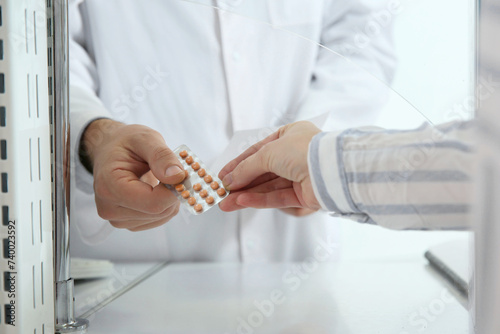 Professional pharmacist giving pills to customer in drugstore, closeup