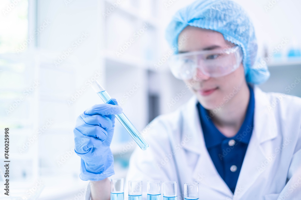 Closeup female woman scientist's hand holding blue liquid chemical chemistry test tube working in analyze science laboratory research experiment Closeup female woman scientist's hand holding blue liquid chemical chemistry test tube working in analyze science laboratory research experiment