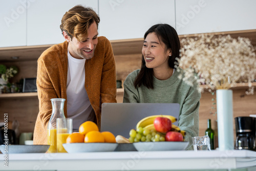 Adult couple using laptop together at kitchen counter