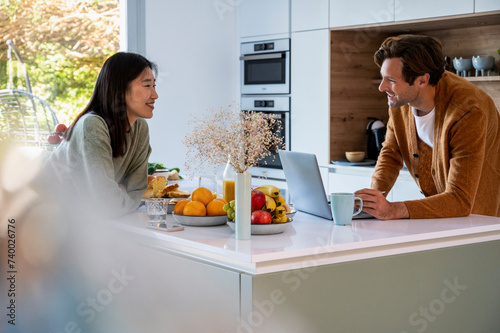 Adult man using laptop while having breakfast with friend