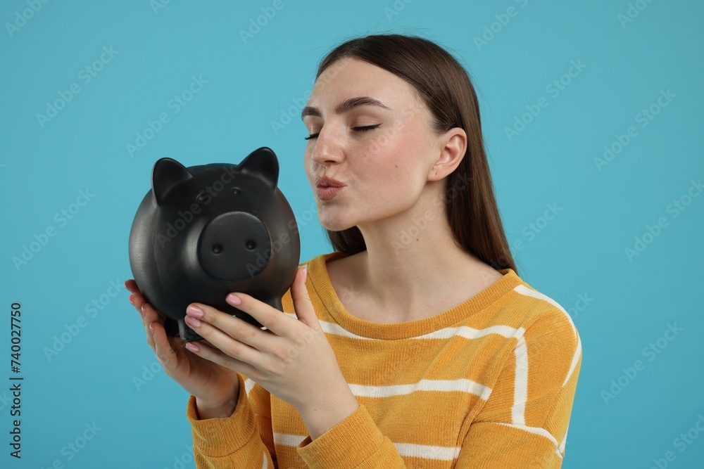 Fototapeta premium Woman with piggy bank on light blue background