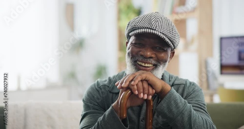 Face, cane and and senior black man with disability on sofa in living room of retirement home to relax. Portrait, funny and elderly person laughing in apartment with wooden walking stick for balance photo